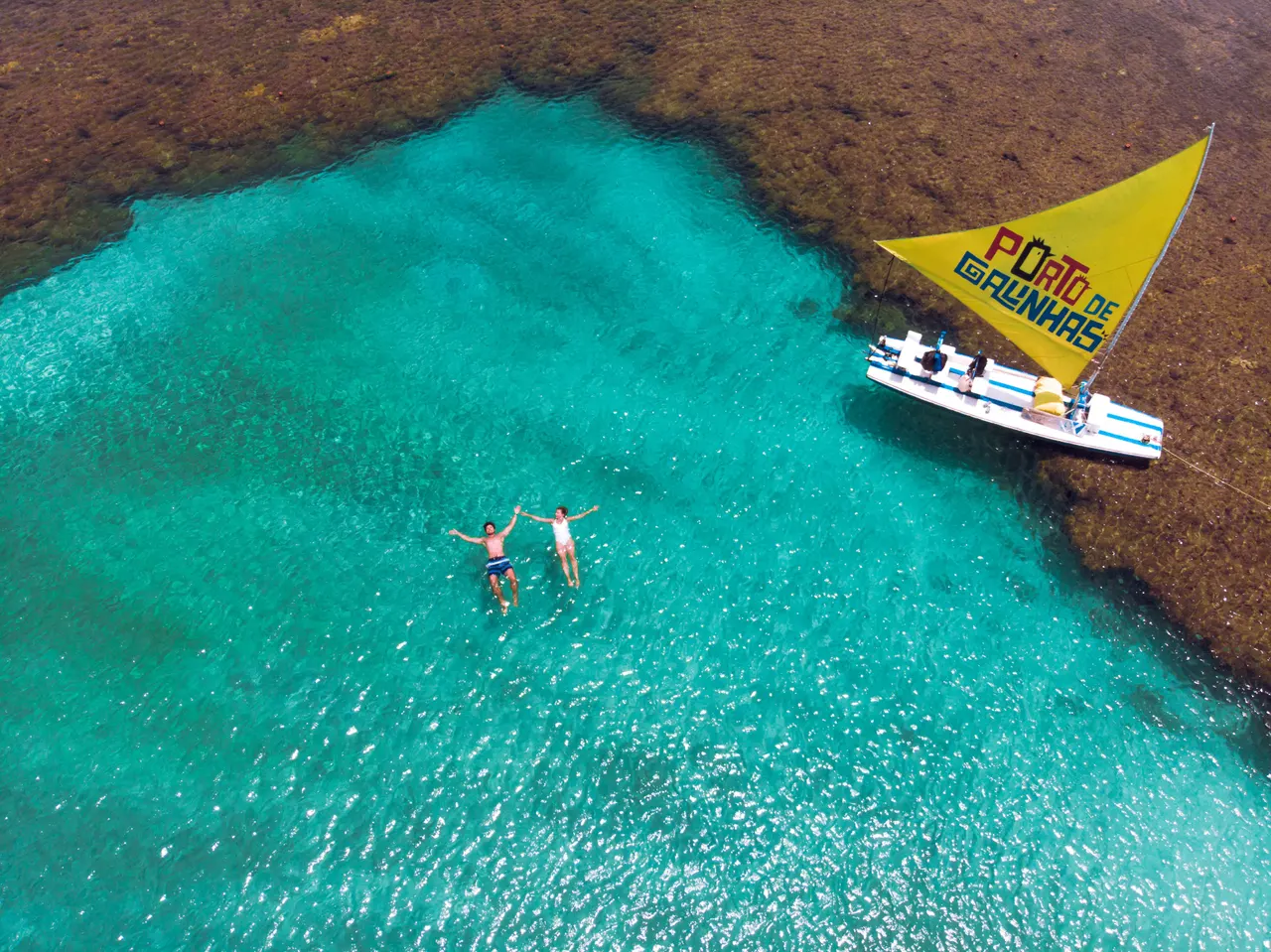 Vista aérea de banhistas e jangada nas águas cristalinas de Porto de Galinhas, em Pernambuco